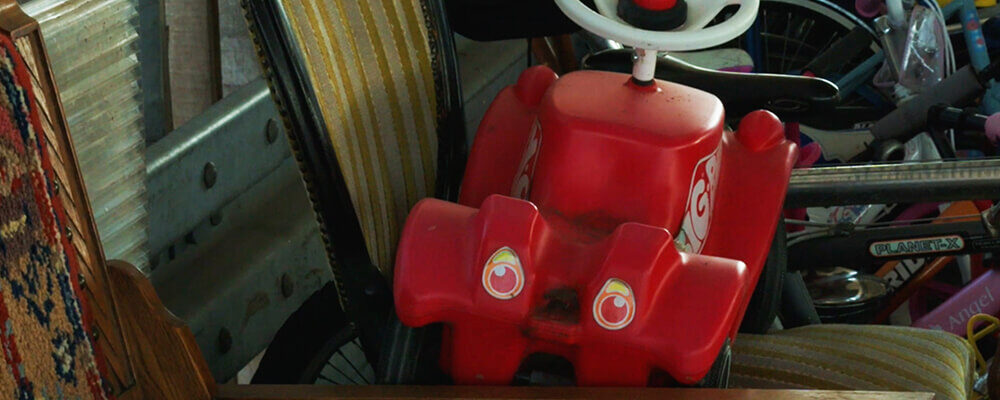 Rode kinderwagen met ogen als koplampen ligt tussen weggegooide voorwerpen