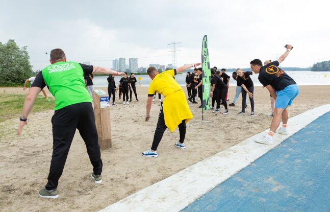 Buurtsportcoaches en scholieren van middelbare school Echnaton doen oefeningen op het strand bij het Weerwater