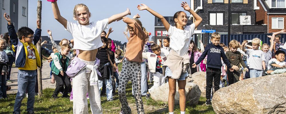 Basisschoolleerlingen spelen gezamenlijk op een veld ergens in Almere.