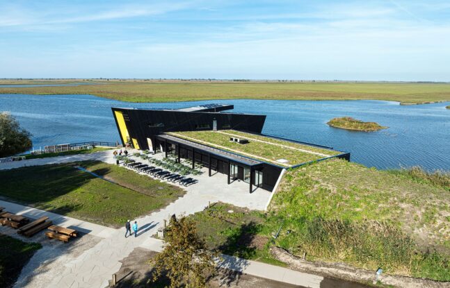 Luchtfoto van het vernieuwde Natuurbelevingcentrum de Oostvaarders in een waterrijke omgeving.