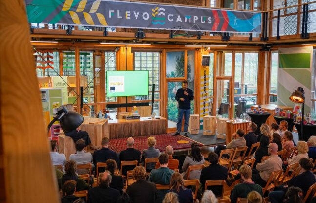 Presentatie tijdens het Food Pioneers-programma bij Flevo Campus, met publiek en een spreker voor een groot scherm in een lichte, houten ruimte - Foto: Nicolas Brenninkmeijer